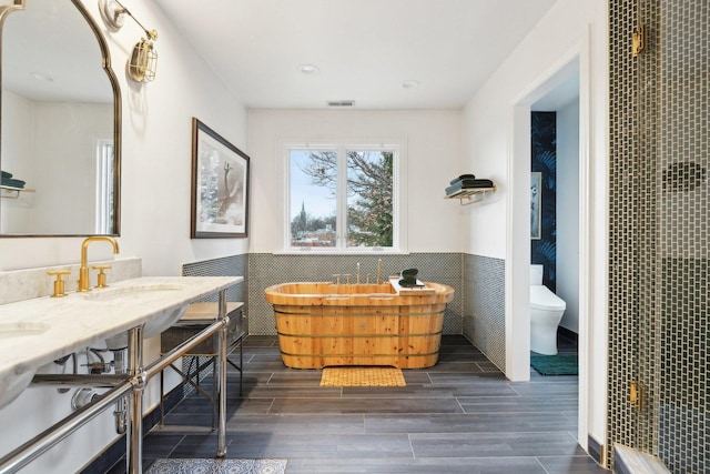 bathroom featuring vanity, toilet, and tile walls