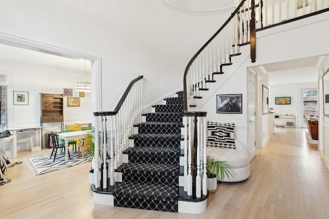 stairs with hardwood / wood-style flooring and a towering ceiling