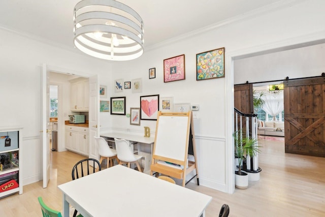 dining area with crown molding, a barn door, and light wood-type flooring