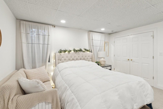 carpeted bedroom featuring a paneled ceiling and a closet