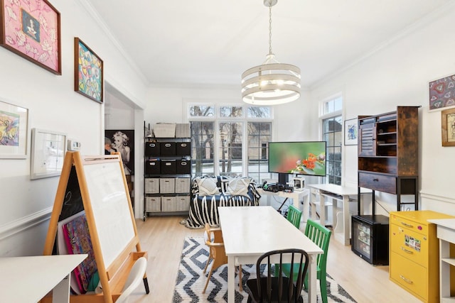 dining area featuring crown molding, a chandelier, and light hardwood / wood-style floors