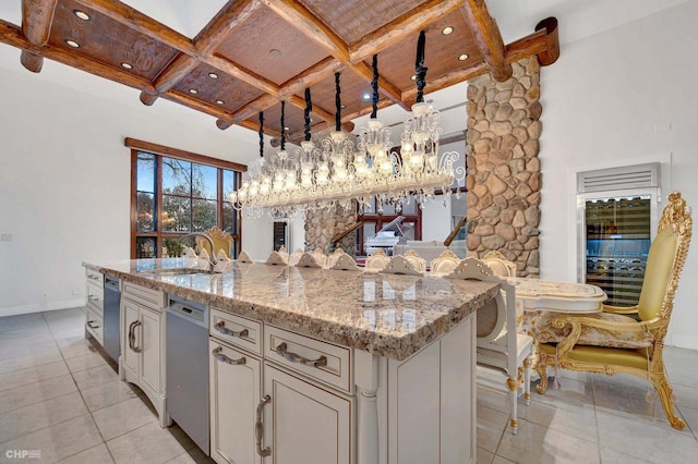 kitchen featuring sink, a breakfast bar, coffered ceiling, a center island with sink, and decorative light fixtures