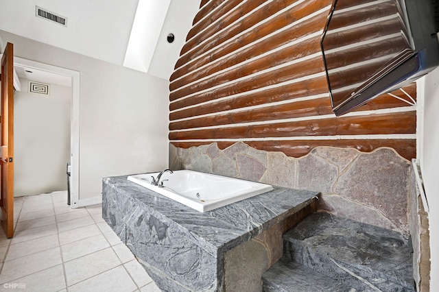 bathroom featuring lofted ceiling, tile patterned floors, and tiled bath