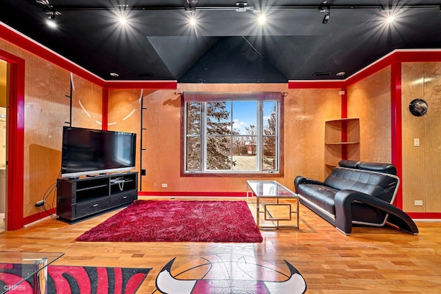 living room featuring wood-type flooring, vaulted ceiling, and rail lighting