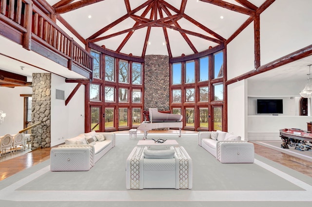 living room featuring beamed ceiling, a wealth of natural light, a notable chandelier, and high vaulted ceiling