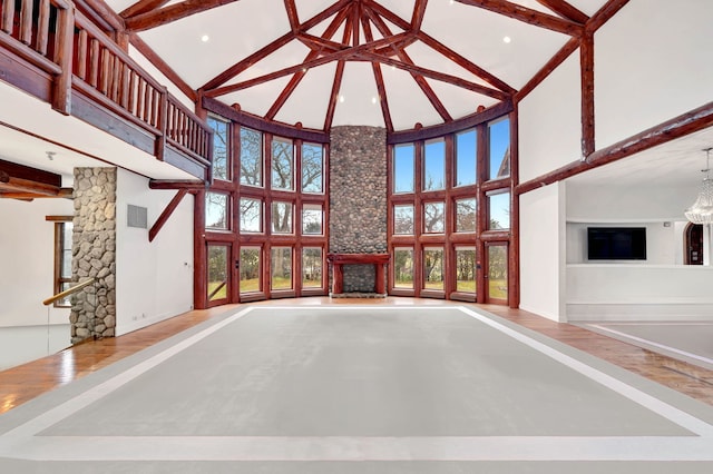 unfurnished living room featuring beam ceiling, wood-type flooring, high vaulted ceiling, and an inviting chandelier