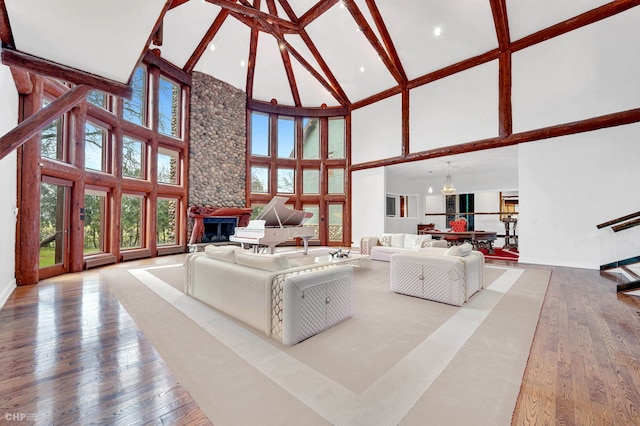 living room featuring wood-type flooring, high vaulted ceiling, an inviting chandelier, and a fireplace