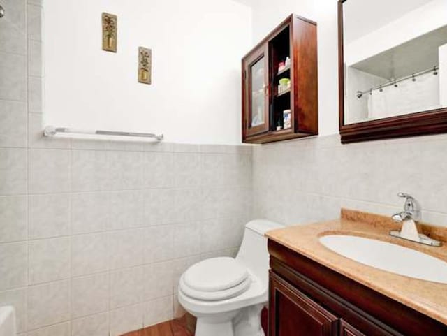 bathroom featuring tile walls, vanity, wood-type flooring, a shower with curtain, and toilet