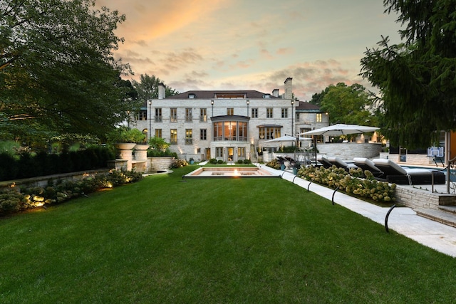 back house at dusk with a lawn