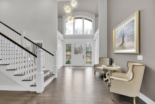 entryway featuring a towering ceiling, dark hardwood / wood-style flooring, and a chandelier