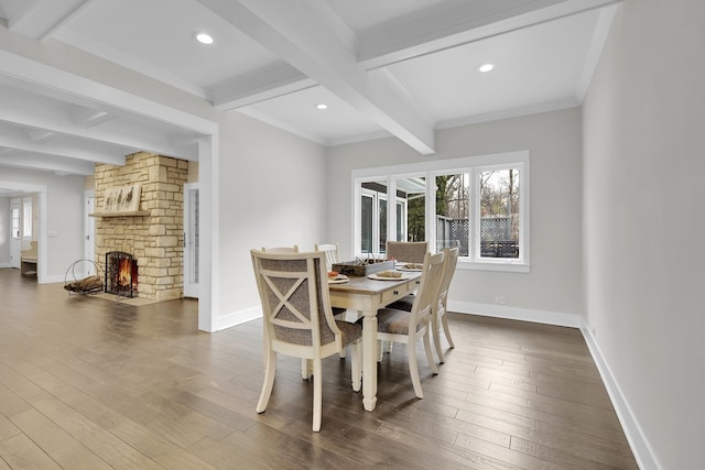 dining space with crown molding, a fireplace, wood-type flooring, and beam ceiling