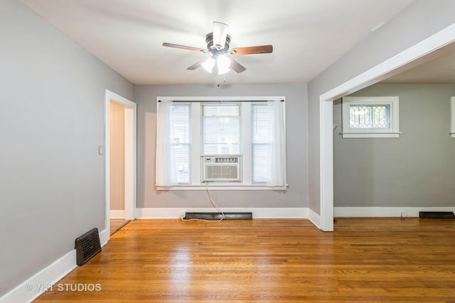 empty room with cooling unit, ceiling fan, and light hardwood / wood-style floors