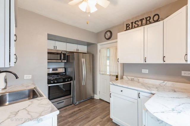 kitchen with appliances with stainless steel finishes, sink, white cabinets, and light hardwood / wood-style floors