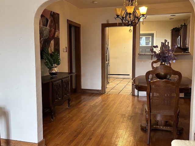 dining area featuring an inviting chandelier, a baseboard radiator, and light wood-type flooring