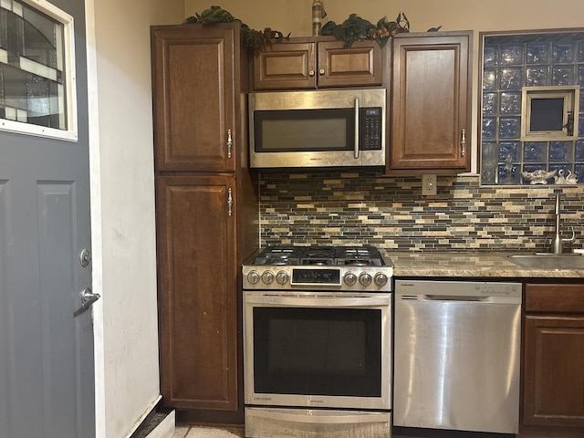 kitchen featuring tasteful backsplash, dark brown cabinetry, appliances with stainless steel finishes, and sink