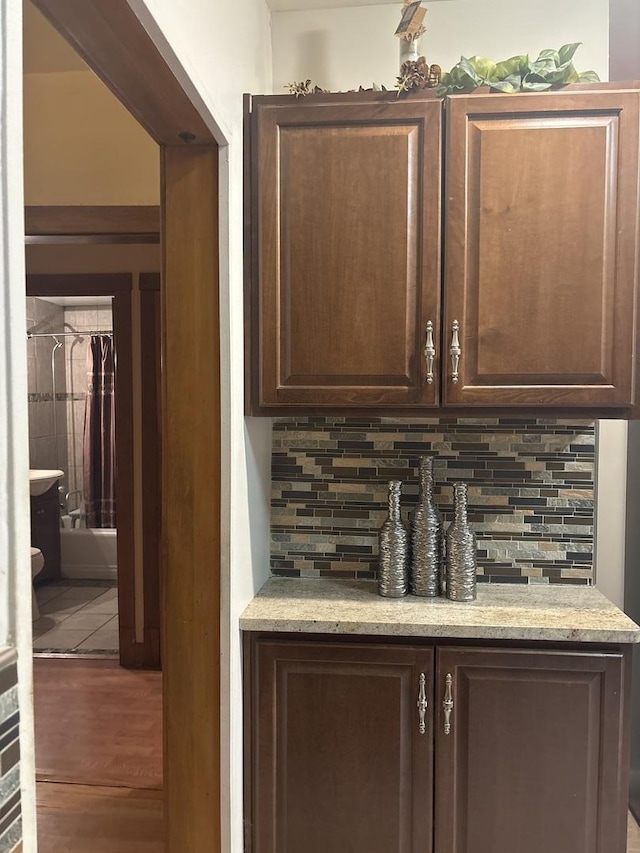 bar featuring dark brown cabinetry and backsplash