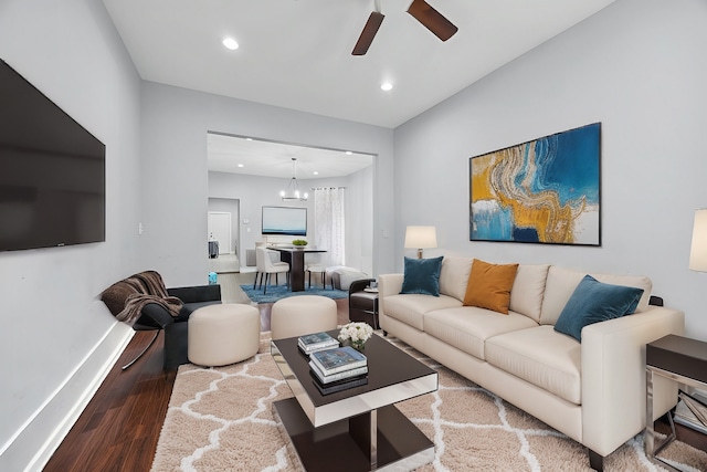 living room with ceiling fan with notable chandelier and hardwood / wood-style floors