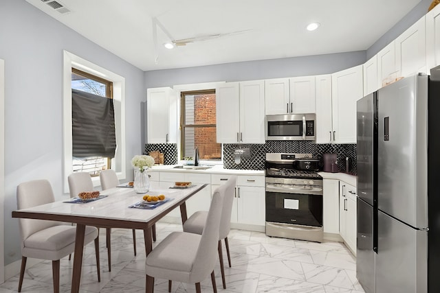 kitchen featuring stainless steel appliances, tasteful backsplash, sink, and white cabinets