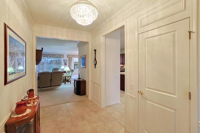 hall with ornamental molding, light colored carpet, and a chandelier