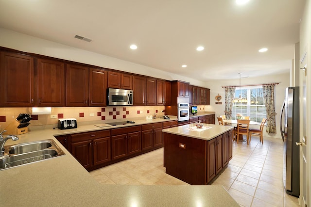 kitchen featuring pendant lighting, tasteful backsplash, sink, a center island, and stainless steel appliances