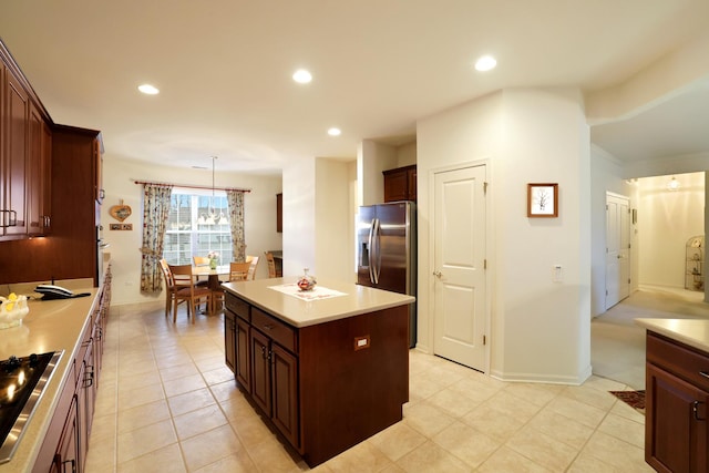 kitchen featuring hanging light fixtures, a center island, light tile patterned floors, cooktop, and stainless steel refrigerator with ice dispenser