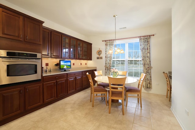 kitchen featuring pendant lighting, oven, a chandelier, and tasteful backsplash