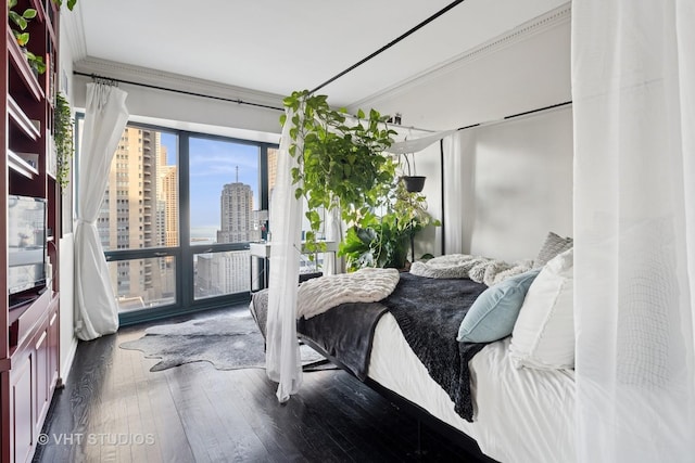 bedroom featuring ornamental molding, wood-type flooring, and a city view