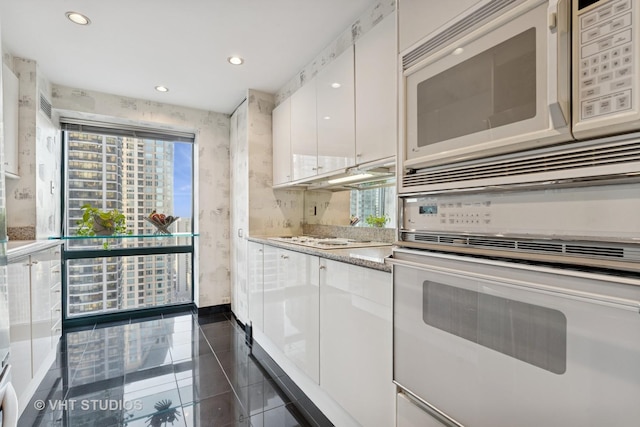 kitchen with white appliances, white cabinetry, light countertops, and recessed lighting