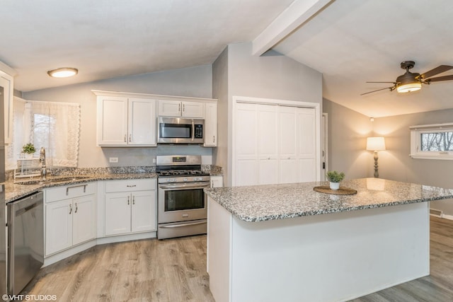 kitchen with sink, vaulted ceiling with beams, white cabinets, and appliances with stainless steel finishes