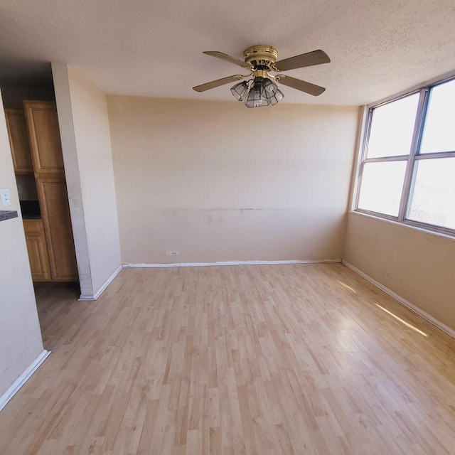 empty room featuring ceiling fan, a textured ceiling, and light wood-type flooring