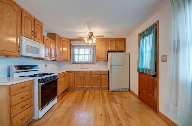 kitchen with ceiling fan, sink, white appliances, and light hardwood / wood-style floors