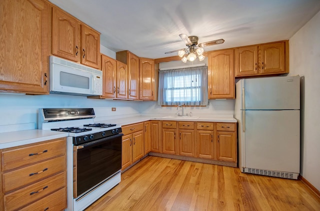 kitchen with ceiling fan, sink, white appliances, and light hardwood / wood-style flooring