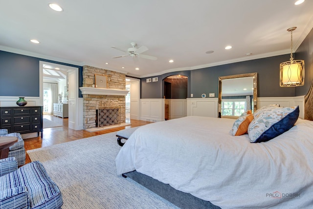 bedroom with ceiling fan, wood-type flooring, a fireplace, and ornamental molding