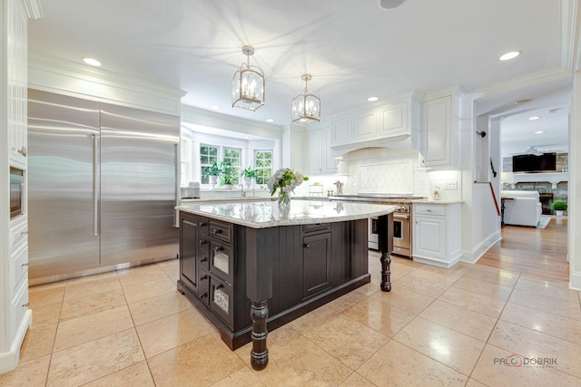 kitchen with decorative light fixtures, a kitchen island, white cabinets, stainless steel appliances, and backsplash