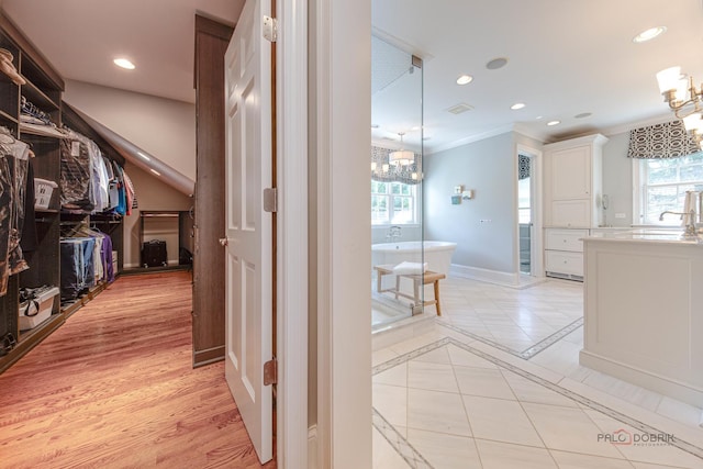 hall featuring ornamental molding, light tile patterned floors, and a notable chandelier