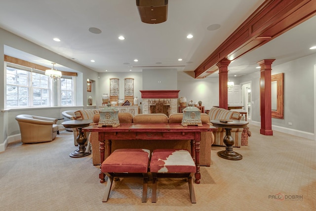 carpeted living room with a stone fireplace and decorative columns