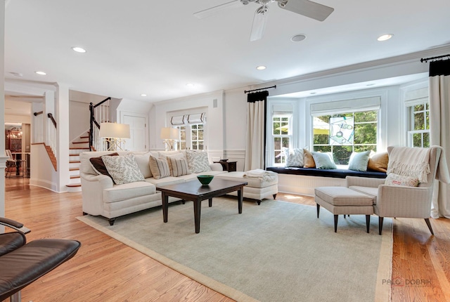 living room with ornamental molding, ceiling fan, and light wood-type flooring