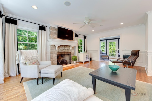 living room with crown molding, ceiling fan, a fireplace, and light hardwood / wood-style floors