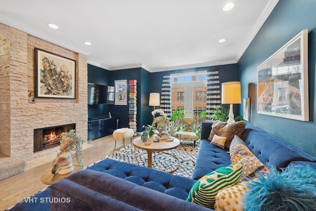 living room with ornamental molding, a stone fireplace, hardwood / wood-style floors, and french doors