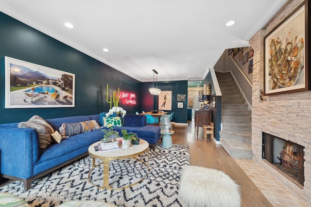 living room featuring ornamental molding, a stone fireplace, and light wood-type flooring