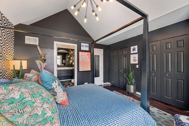 bedroom with an inviting chandelier, lofted ceiling, dark hardwood / wood-style floors, and ensuite bathroom