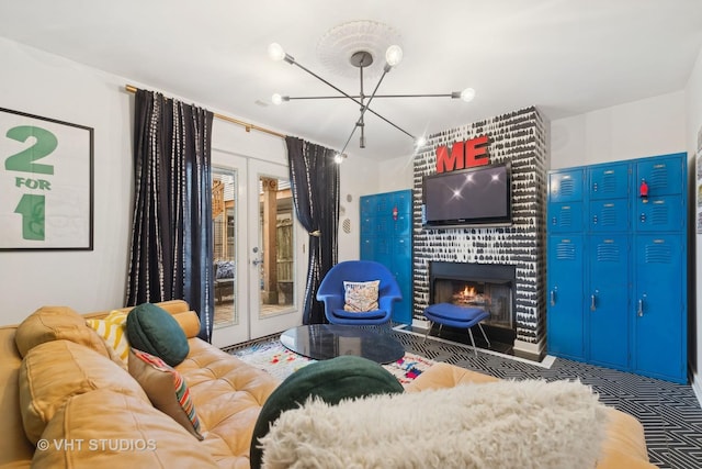 living room with an inviting chandelier, a brick fireplace, and french doors