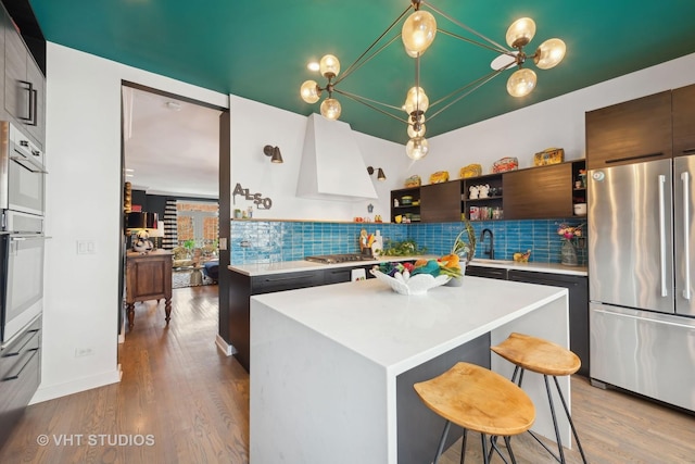 kitchen with stainless steel appliances, premium range hood, a kitchen island, and tasteful backsplash