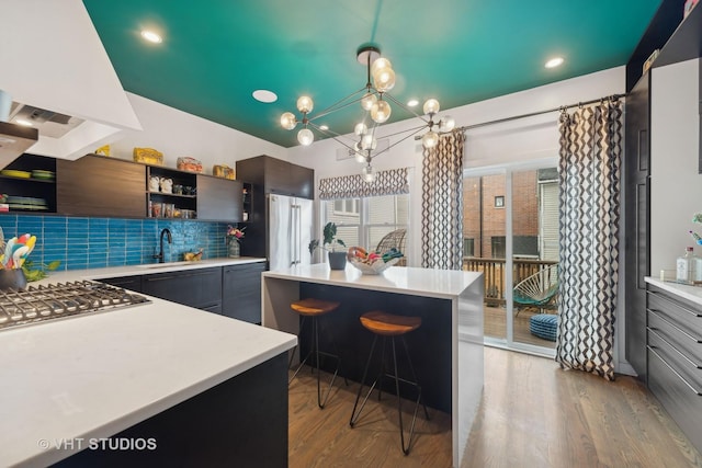 kitchen featuring custom exhaust hood, a kitchen island, sink, and stainless steel gas stovetop