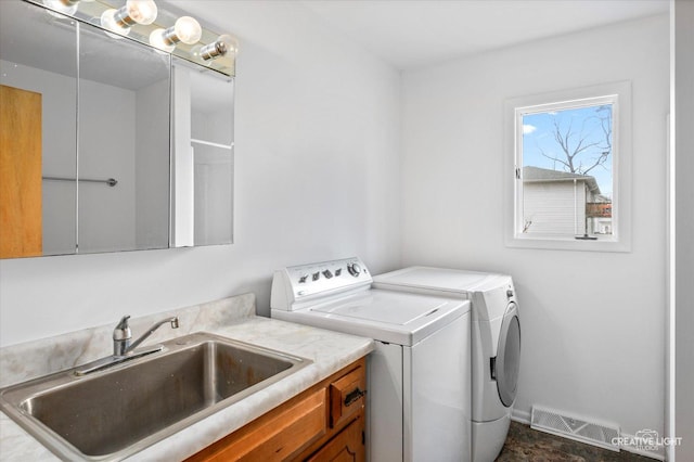 washroom featuring sink, washing machine and dryer, and cabinets