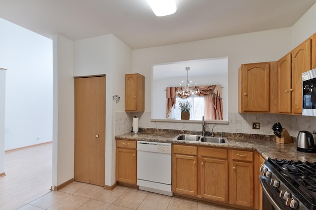 kitchen with appliances with stainless steel finishes, sink, decorative backsplash, hanging light fixtures, and light tile patterned floors