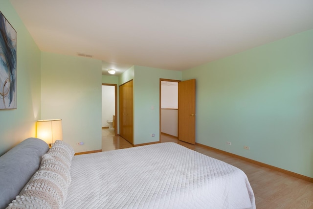 bedroom with ensuite bath, light hardwood / wood-style floors, and a closet