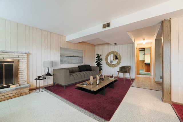 living room featuring a fireplace and wooden walls