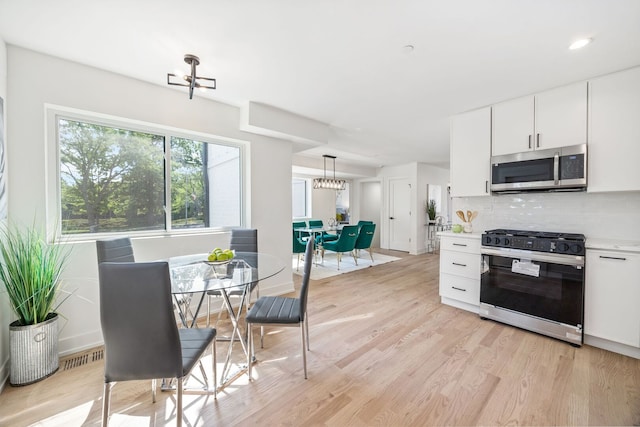 4932 Brummel St, Skokie, IL 60077 - kitchen with range with gas stovetop, stainless steel microwave, a chandelier, tasteful backsplash, and light wood finished floors