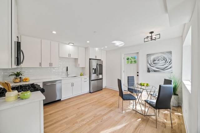 4932 Brummel St, Skokie, IL 60077 - kitchen featuring stainless steel appliances, tasteful backsplash, light wood-type flooring, white cabinets, and a chandelier